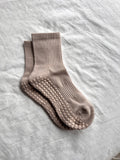 Pair of beige socks with textured sole on a light gray fabric background